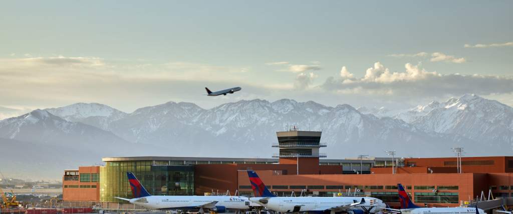 A plane on takeoff above Salt Lake International Airport with a foggy mountainscape in the background.